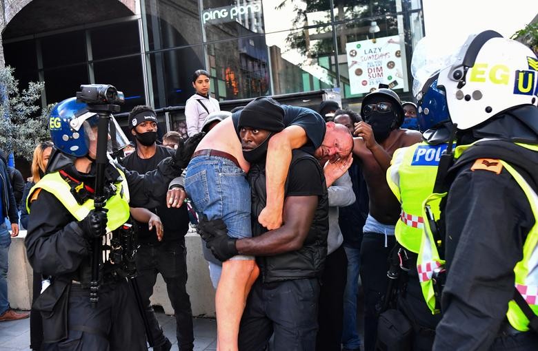 A protester carries an injured counter-protester to safety, near the Waterloo station during a Black Lives Matter protest in London, Britain. REUTERS/Dylan Martinez   